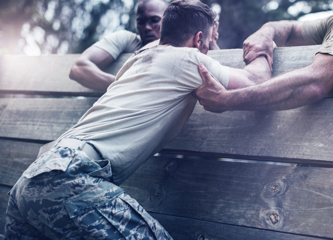 solidiers assisting each other over a wall in training